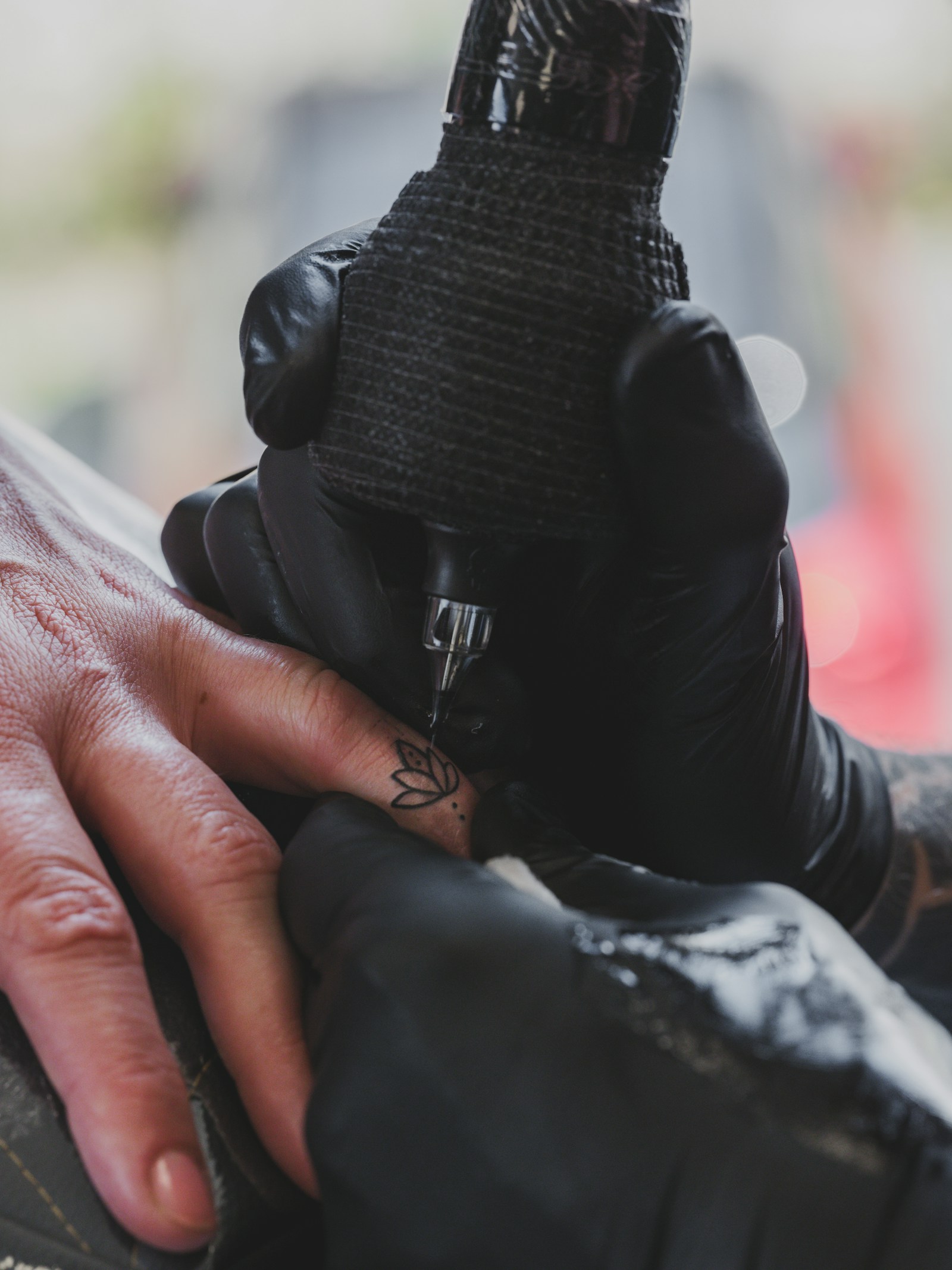 Tatuador con guantes negros tatuando los dedos a máquina